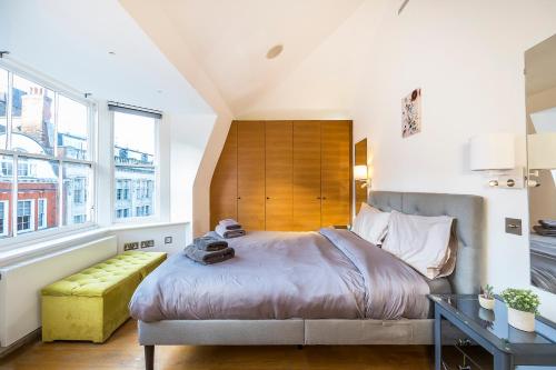 ein Schlafzimmer mit einem großen Bett und einer gelben Bank in der Unterkunft Lux Duplex near Oxford St in London