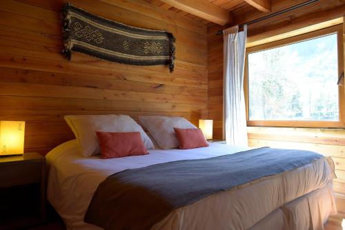 a bedroom with a bed in a log cabin at Patagonia Lodge in Las Trancas