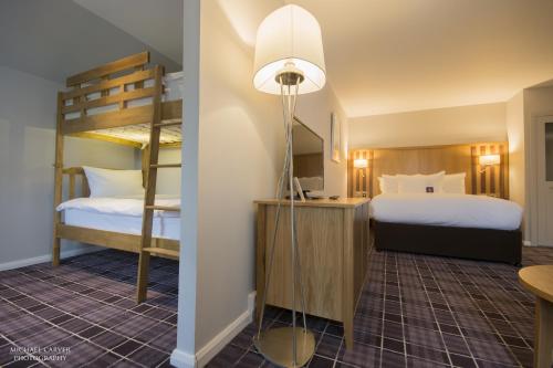 a room with two bunk beds and a desk with a lamp at Kingsmills Hotel in Inverness