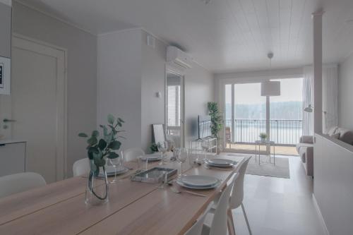 a white room with a dining table and a large window at Pramea Apartments Kultaniemi in Kuopio