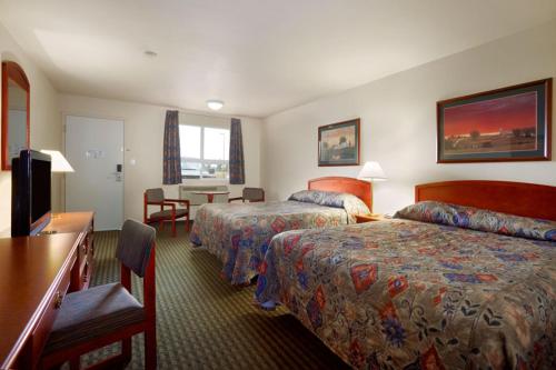 a hotel room with two beds and a table at Travelodge Hotel by Wyndham Weyburn in Weyburn