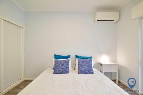 a bedroom with a bed with blue pillows at T1 Perto da Praia in Armação de Pêra