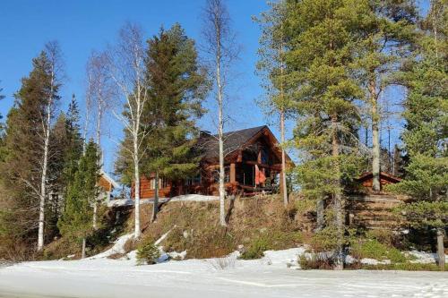 a log cabin in the woods with snow and trees at Riverside Villa in Rovaniemi