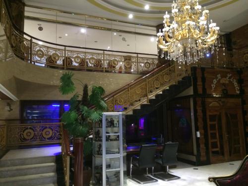 a lobby with a chandelier and a staircase with chairs at Sun Beach Hôtel in Cotonou