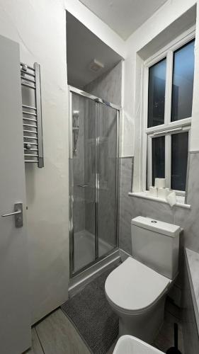 a bathroom with a toilet and a glass shower at Wandsworth Guest Rooms 64 in London