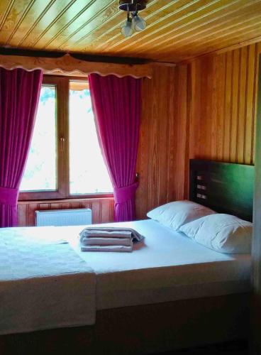een slaapkamer met een bed met paarse gordijnen bij Rize Doğa Home 