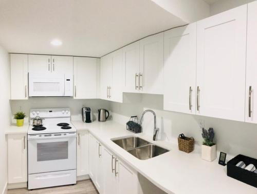 a kitchen with white cabinets and a white stove top oven at Bookyourhome in Langley