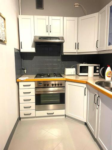 a kitchen with white cabinets and a stove top oven at Metro Bemowo Comfort Apartment in Warsaw