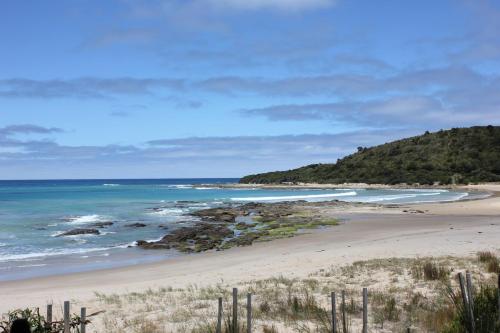 a beach with rocks and the ocean and a hill at Allawah at Kennett in Kennett River