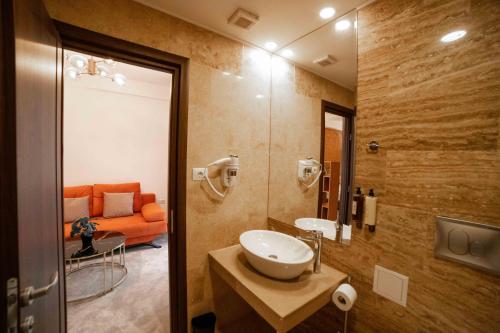 a bathroom with a sink and an orange couch at Bucharest Airport Accomodation in Otopeni