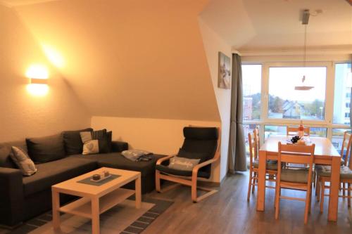 een woonkamer met een bank en een tafel bij Ferienwohnung mit Seeblick und Schwimmbadnutzung in Cuxhaven in Cuxhaven