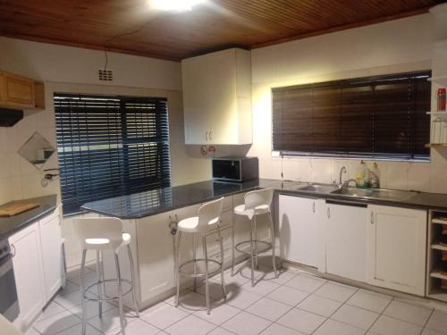 a kitchen with white cabinets and bar stools at Cape Town 5 bedroom house Belhar in Cape Town