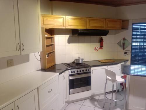 a kitchen with white cabinets and a stove and a chair at Cape Town 5 bedroom house Belhar in Cape Town