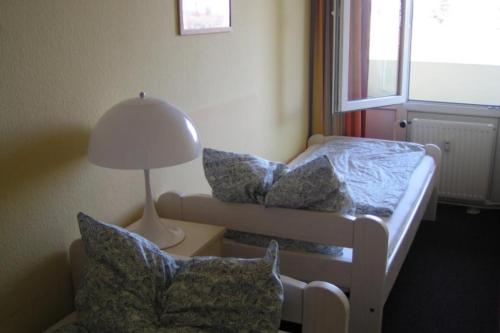Schönberg in HolsteinにあるFerienappartement E223 für 2-4 Personen an der Ostseeのベッド、ランプ、椅子が備わる小さな客室です。