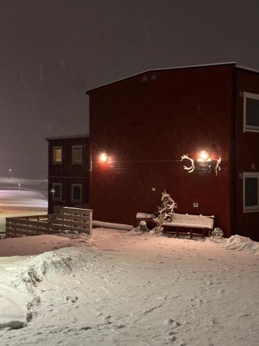 um edifício na neve à noite com luzes em Haugen Pensjonat Svalbard em Longyearbyen