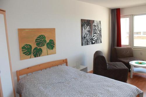 a bedroom with a bed and a chair and paintings at Ferienappartement K111 für 2-4 Personen in Strandnähe in Schönberg in Holstein