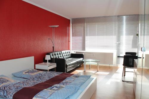 1 dormitorio con paredes rojas, 1 cama y 1 sofá en Ferienappartement K1207 für 2-4 Personen mit Ostseeblick, en Schönberg in Holstein