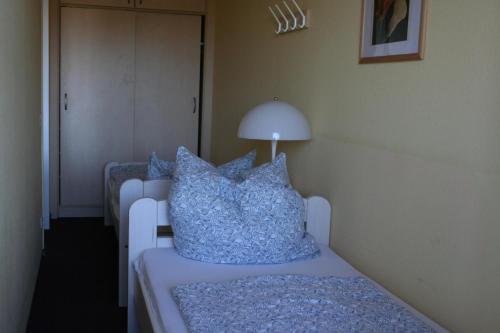 ブラズィリアンにあるFerienappartement E229 für 2-4 Personen an der Ostseeのベッドルーム1室(青い枕とランプ付きのベッド1台付)