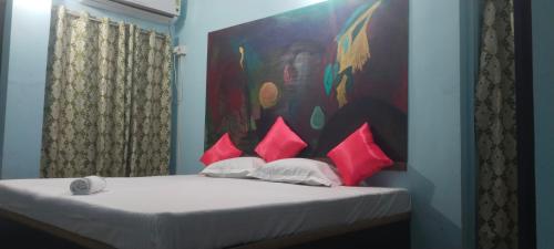 1 cama con almohadas rosas y una pintura en la pared en Blue Cherry Guest House en Calcuta
