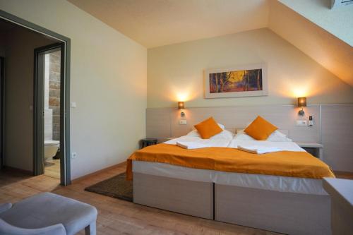 a bedroom with a bed with orange sheets and orange pillows at Szalajka Fogadó és Étterem in Szilvásvárad