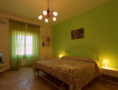 a bedroom with a bed with green walls and a chandelier at Country Salenthouse in Marina di Mancaversa