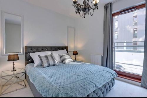 1 dormitorio con 1 cama con lámpara de araña y ventana en Exclusive Apartment Motlawa River Oldtown, en Gdansk
