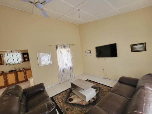 a living room with a couch and a tv at Nicely Furnished Comfortable Holiday Apartment Home at Yarambamba Estate in Yundum
