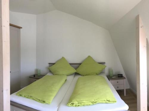 a bed with two lime green pillows on it at Seeblick 2 in Dahme
