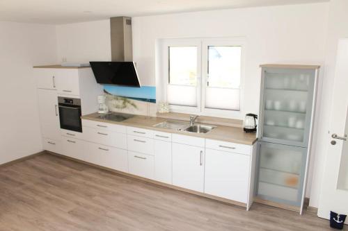 a white kitchen with a sink and a refrigerator at Zur Strandwiese W6 in Dahme