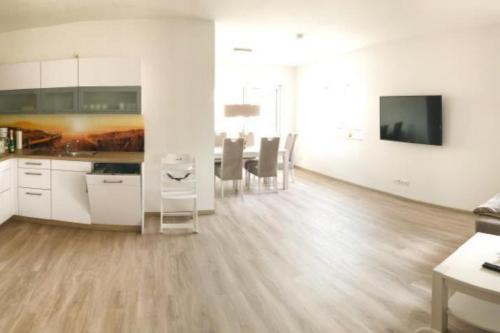 una cucina e una sala da pranzo con armadi bianchi e pavimenti in legno di Zur Strandwiese W3 a Dahme