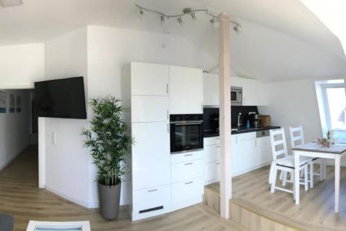 a kitchen with white cabinets and a table with a potted plant at Seeblick 1 in Dahme