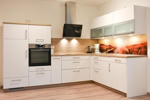 a white kitchen with white cabinets and appliances at Zur Strandwiese W1 in Dahme