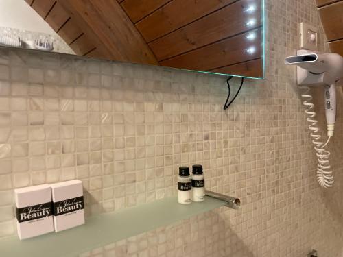 a bathroom with a shelf with three bottles on it at Hotel Noventa in Noventa Vicentina