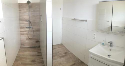 a white bathroom with a shower and a sink at Zur Strandwiese W5 in Dahme