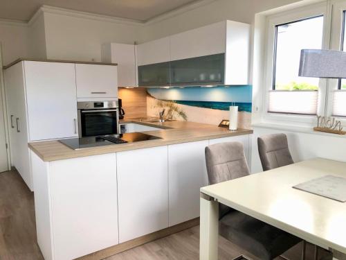 a kitchen with white cabinets and a table with chairs at Zur Strandwiese W5 in Dahme