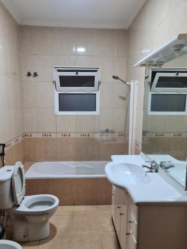 ein Badezimmer mit einer Badewanne, einem WC und einem Waschbecken in der Unterkunft Pastello guest house in Maputo