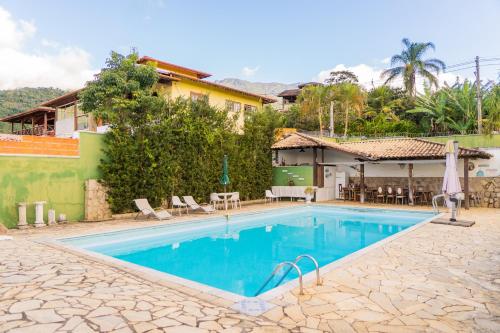 a swimming pool in front of a house at Bela Ilha Guest House in Ilhabela