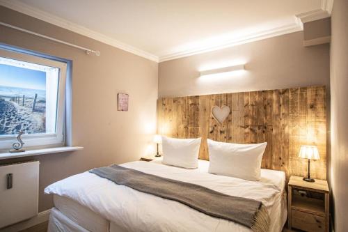 ヴェニングシュテットにあるNordseekrabbeのベッドルーム1室(大型ベッド1台、木製ヘッドボード付)