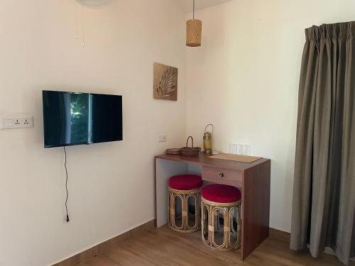 a room with two stools and a tv on the wall at Coffee Cradle Wayanad Luxuorios Private Tree House - Inside 2 Acre Coffee Plantation in Mananthavady