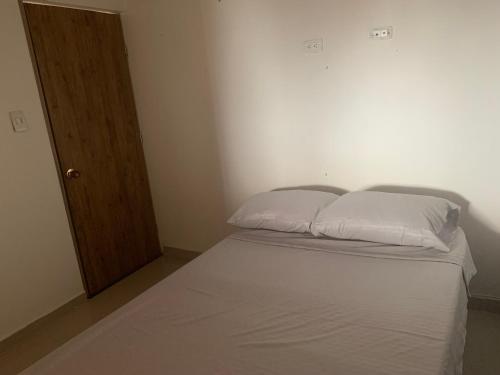 um quarto com uma cama com duas almofadas brancas em Alojamiento en Medellín em Medellín