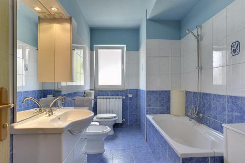 La salle de bains bleue et blanche est pourvue d'une baignoire, de toilettes et d'un lavabo. dans l'établissement Villa Semy, à Lindar