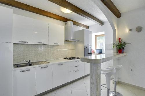 cocina blanca con armarios blancos y encimera en Villa Bella, en Lupoglav