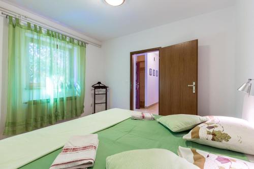 a bedroom with a large green bed and a window at Apartment Doris in Banjole