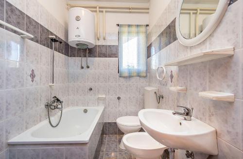 een badkamer met een wastafel, een toilet en een bad bij Casa Sissano in Šišan