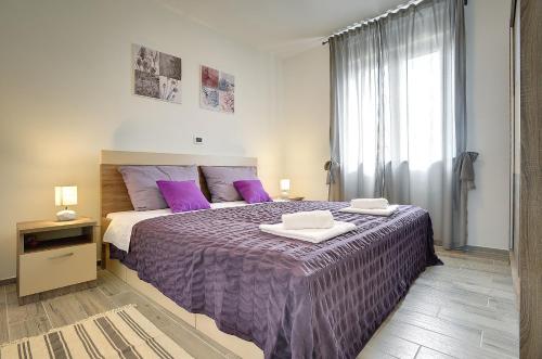 a bedroom with a large bed with purple sheets at Villa Rudy in Štinjan