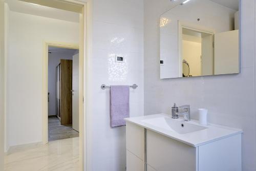 a white bathroom with a sink and a mirror at Villa Rudy in Štinjan