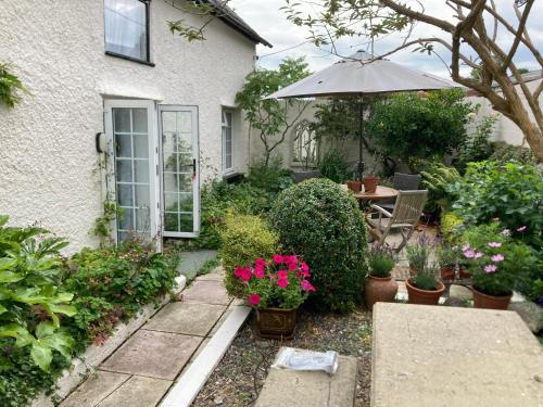 um jardim com uma mesa e um guarda-sol em Bryntirion Farmhouse Apartment with Hot Tub em Llanfair Caereinion
