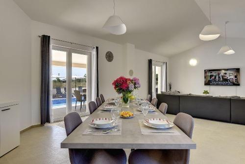 a dining room with a long table with flowers on it at Villa mit Pool und klimatisierten Schlafzimmern in Vodnjan