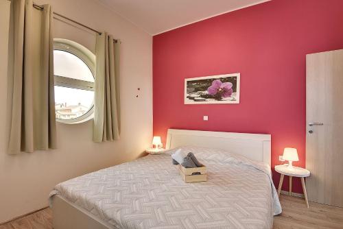 ein Schlafzimmer mit einem Bett mit einer roten Wand in der Unterkunft Modernes Appartement mit Balkon, BBQ, WLAN, Klima in Vodnjan
