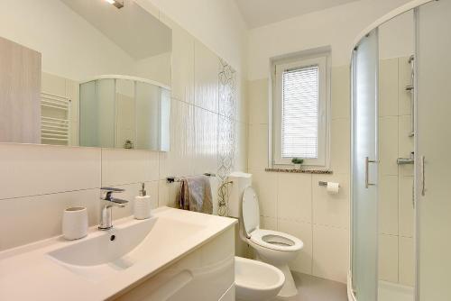 ein weißes Bad mit einem Waschbecken und einem WC in der Unterkunft Modernes Appartement mit Balkon, BBQ, WLAN, Klima in Vodnjan